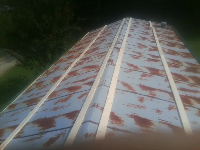 Rusted metal roof panels with new wood purlins before replacement — Storm Damage Roof Repair in Foster by Roofing Brothers